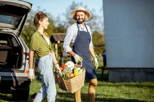 Uomo e donna con verdure fresche vicino alla macchina in campagna — Foto Stock