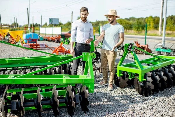 Landbouwkundige met verkoper in de winkel met landbouwmachines — Stockfoto