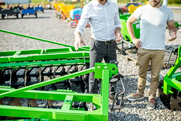 Landbouwkundige met verkoper in de winkel met landbouwmachines — Stockfoto
