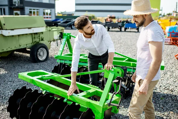 Landbouwkundige met verkoper in de winkel met landbouwmachines — Stockfoto