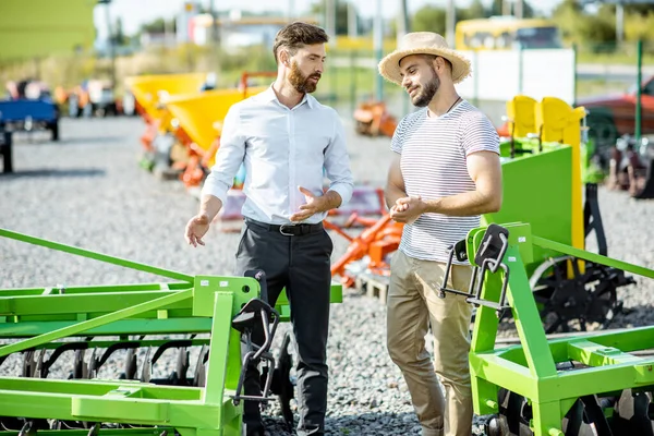 Landbouwkundige met verkoper in de winkel met landbouwmachines — Stockfoto