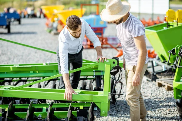 Landbouwkundige met verkoper in de winkel met landbouwmachines — Stockfoto