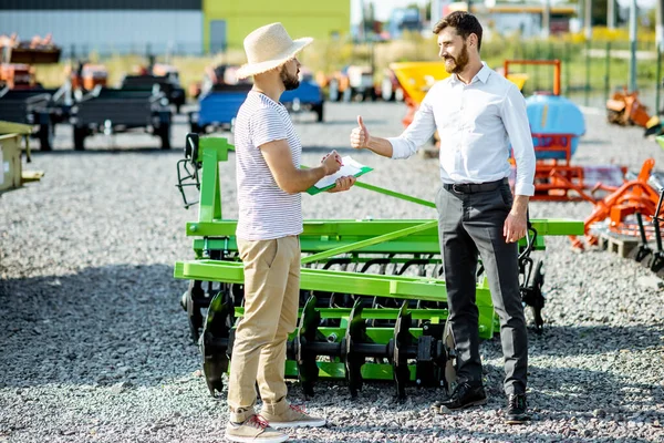 Agronomist with salesman at the shop with agricultural machinery — Stock Photo, Image