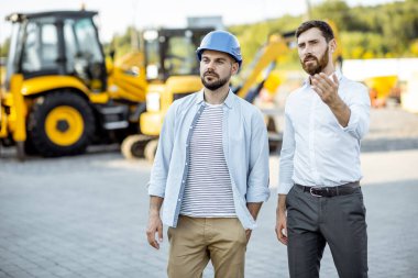 Dükkanda ağır makineli bir satış danışmanı olan bir inşaatçı.