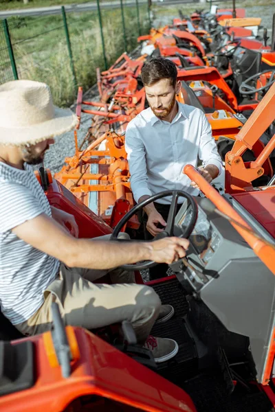นักเกษตรศาสตร์กับพนักงานขาย ใกล้กับรถแทรกเตอร์ข้างนอก — ภาพถ่ายสต็อก