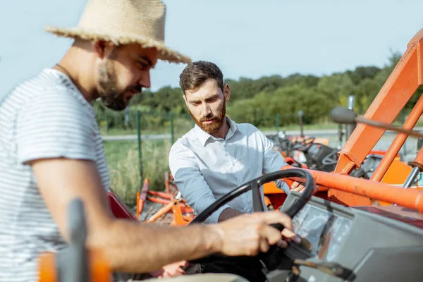 Agronomer med försäljare nära traktorn utomhus — Stockfoto