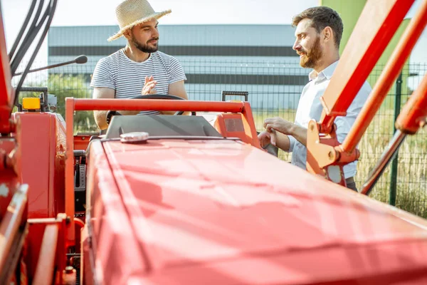 Agronomer med försäljare nära traktorn utomhus — Stockfoto