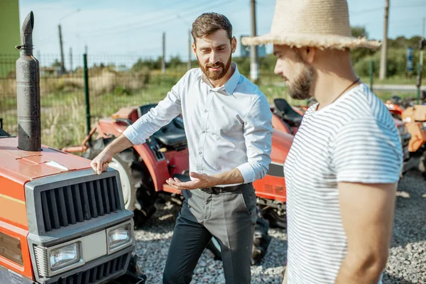 Agronomer med försäljare nära traktorn utomhus — Stockfoto