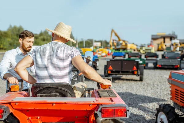 Agronomist met verkoper in de buurt van de trekker buiten — Stockfoto