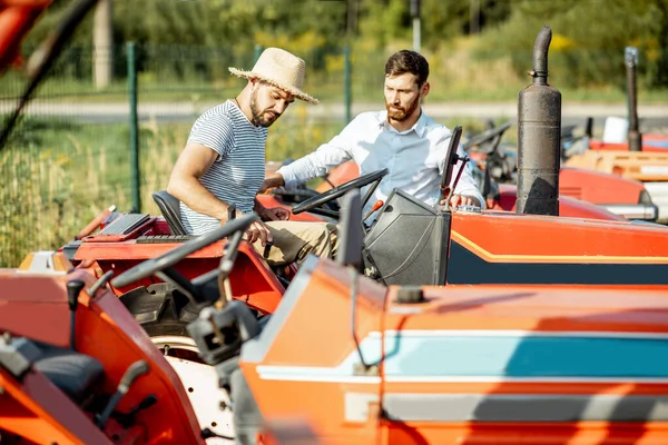 Agronomist met verkoper in de buurt van de trekker buiten — Stockfoto