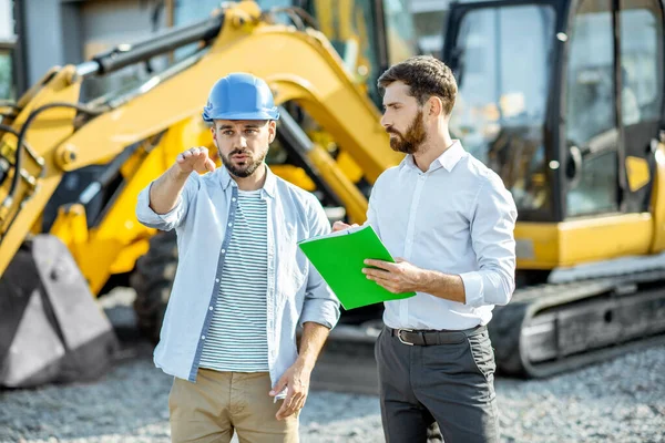 Builder with a sales consultant at the shop with heavy machinery — Stock Photo, Image