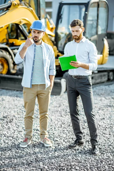 Builder with a sales consultant at the shop with heavy machinery — Stock Photo, Image