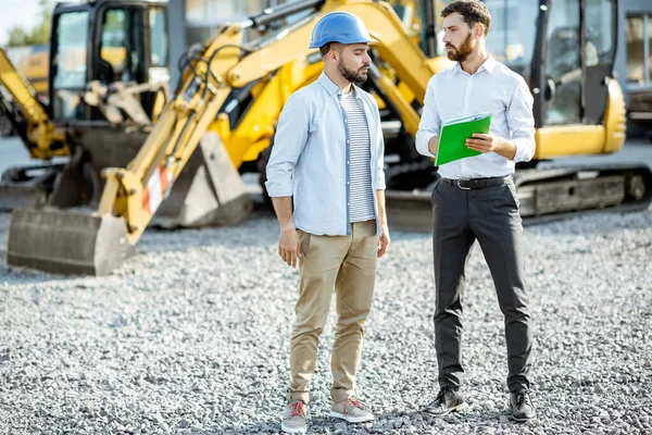 Builder with a sales consultant at the shop with heavy machinery — Stock Photo, Image