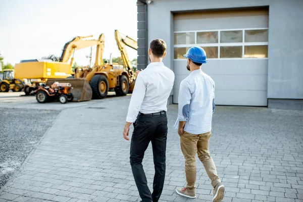 Constructor con un consultor de ventas en la tienda con maquinaria pesada — Foto de Stock