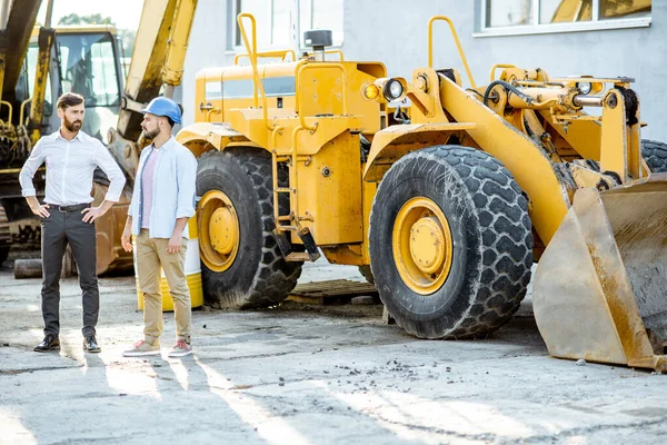 Builder with a sales consultant at the shop with heavy machinery — Stock Photo, Image