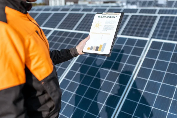 Εργάτης που εξετάζει την παραγωγή ηλεκτρικής ενέργειας σε μονάδα παραγωγής ηλιακής ενέργειας — Φωτογραφία Αρχείου