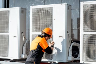 Workman installing outdoor unit of the air conditioner clipart