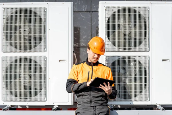 Workman servicing air conditioning or heat pump with digital tablet — Stock Photo, Image
