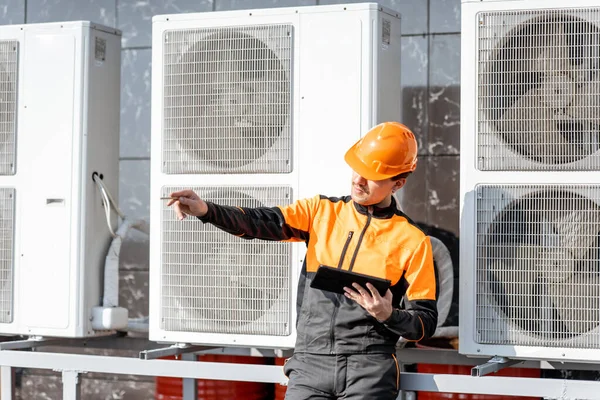 Handwerker wartet Klimaanlage oder Wärmepumpe mit digitalem Tablet — Stockfoto