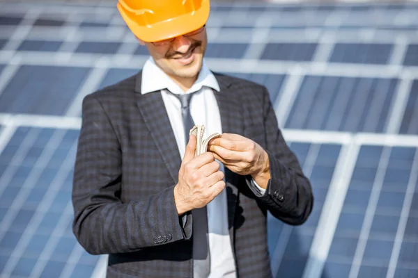 Podnikatel s penězi na solární elektrárně — Stock fotografie