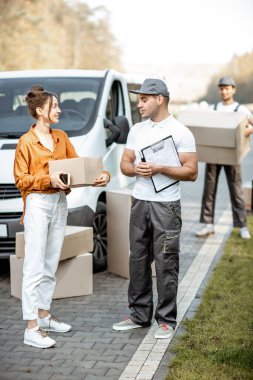 Genç bir kadına arabayla mal getiren adamlar.