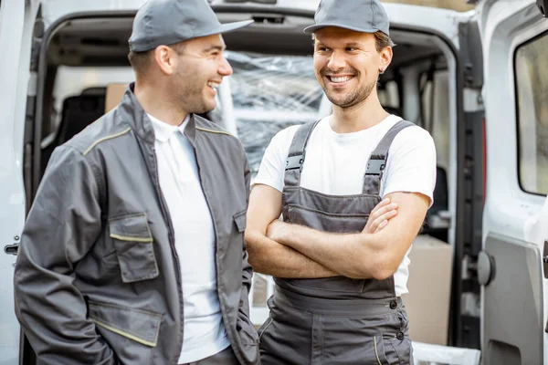 Portrét dvou zaměstnanců doručovatelské společnosti, dodávající zboží autem — Stock fotografie
