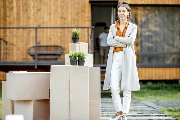 Frau mit Kisten vor einem neuen Haus — Stockfoto