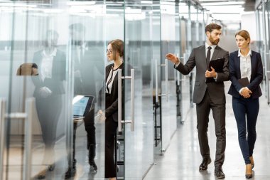 Modern ofis binasının koridorundaki iş adamları.