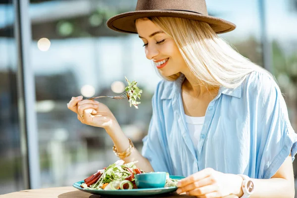 Kvinnan äter sallad på en kafé terrass — Stockfoto