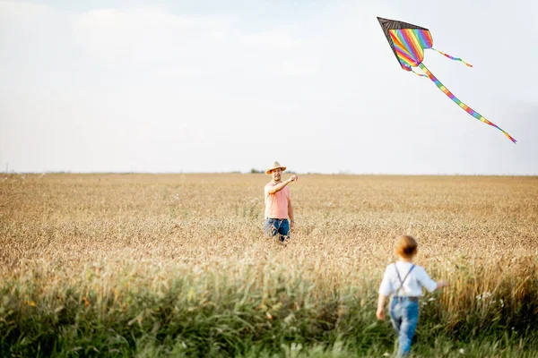 Vader en zoon met vlieger in het veld — Stockfoto