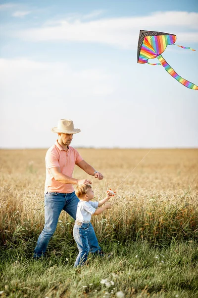 Vader en zoon met vlieger in het veld — Stockfoto