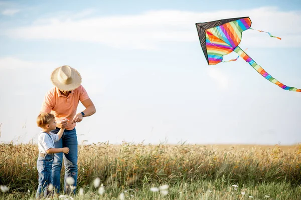 Vader en zoon met vlieger in het veld — Stockfoto