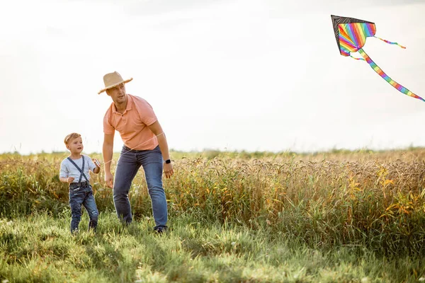 Vader en zoon met vlieger in het veld — Stockfoto