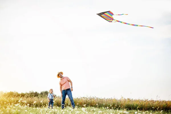 Vader en zoon met vlieger in het veld — Stockfoto