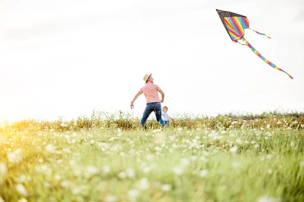 Vader en zoon met vlieger in het veld — Stockfoto