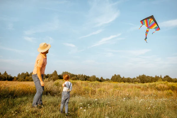 Vader en zoon met vlieger in het veld — Stockfoto