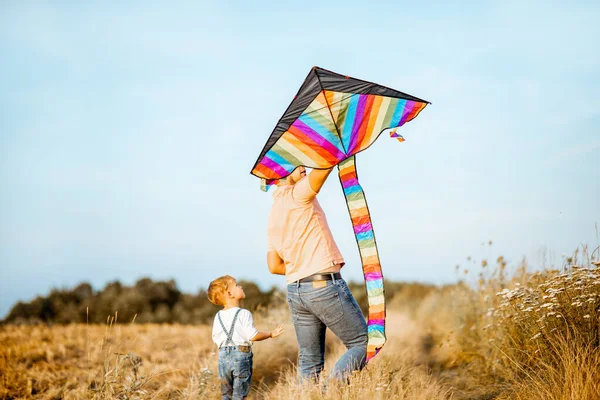 Far och son vandrar med drake på fältet — Stockfoto