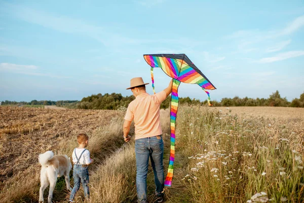 Vader en zoon wandelen met vlieger op het veld — Stockfoto