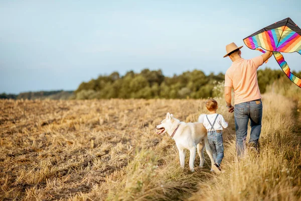 Vader en zoon wandelen met vlieger op het veld — Stockfoto