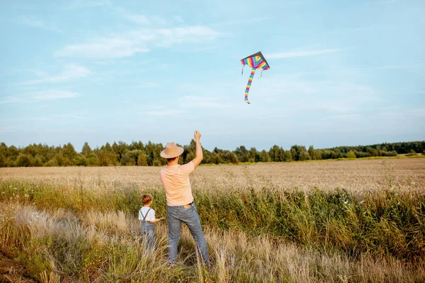 Vader en zoon met vlieger in het veld — Stockfoto