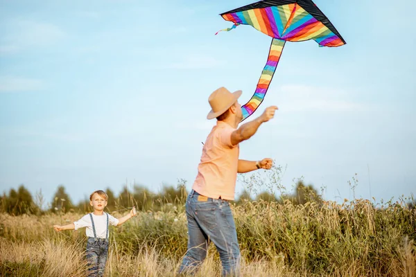 Vader en zoon met vlieger in het veld — Stockfoto