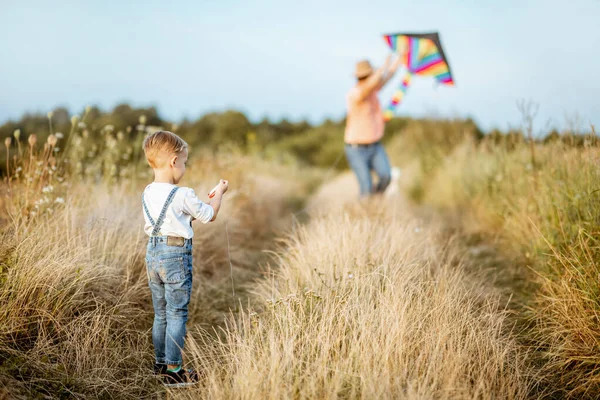 Vader en zoon met vlieger in het veld — Stockfoto