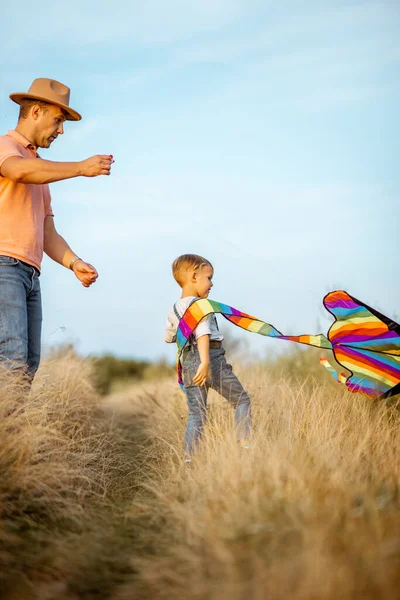 Vader en zoon met vlieger in het veld — Stockfoto