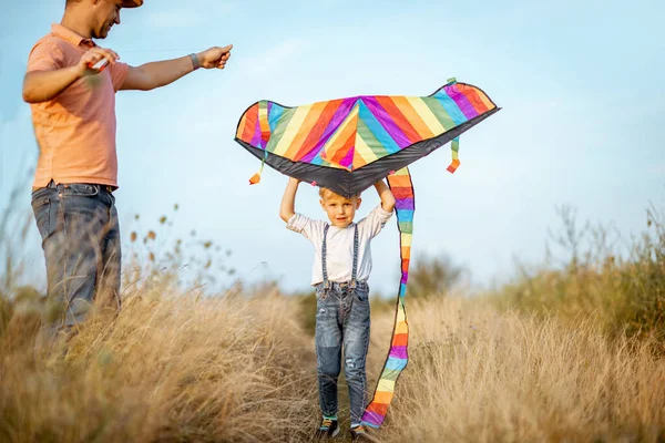 Vader en zoon met vlieger in het veld — Stockfoto