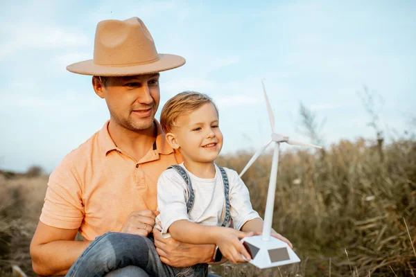 Vater und kleiner Sohn spielen mit Windkraftanlage — Stockfoto