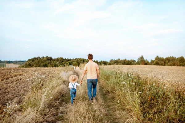 Vader en zoon wandelen in het veld — Stockfoto