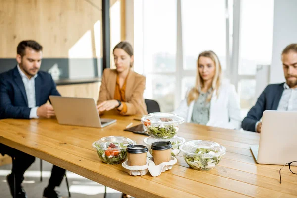 Office employees with healthy takeaway food indoors