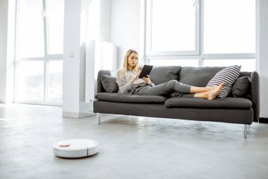 Otomatik elektrik süpürgesi çalışırken kadın dinleniyor