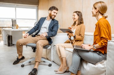 Erkek, kadın meslektaşlarıyla ofiste eğleniyor.