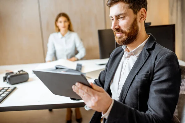 Man arbetar på den digitala surfplattan med kollegor på kontoret — Stockfoto